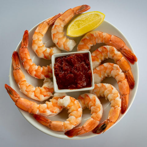 jumbo shrimp cocktail on a plate with lemon and cocktail sauce
