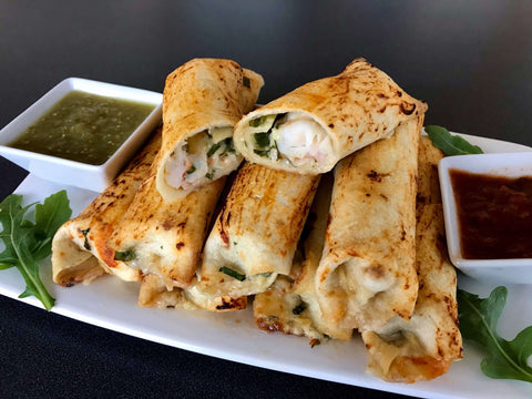 baked shrimp taquitos on a serving plate with green and red salsa