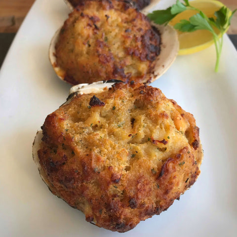 baked stuffed clams on a white plate with lemon and parsley on the side