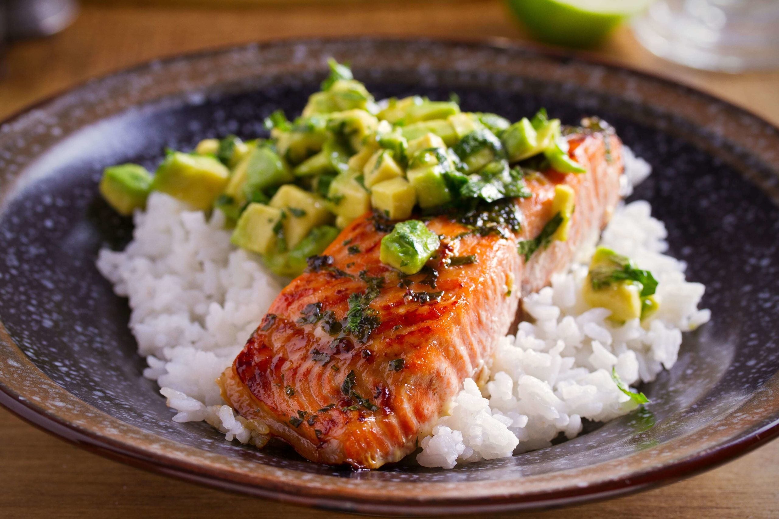 Salmon portion with avocado lime coriander salsa with white rice on a plate