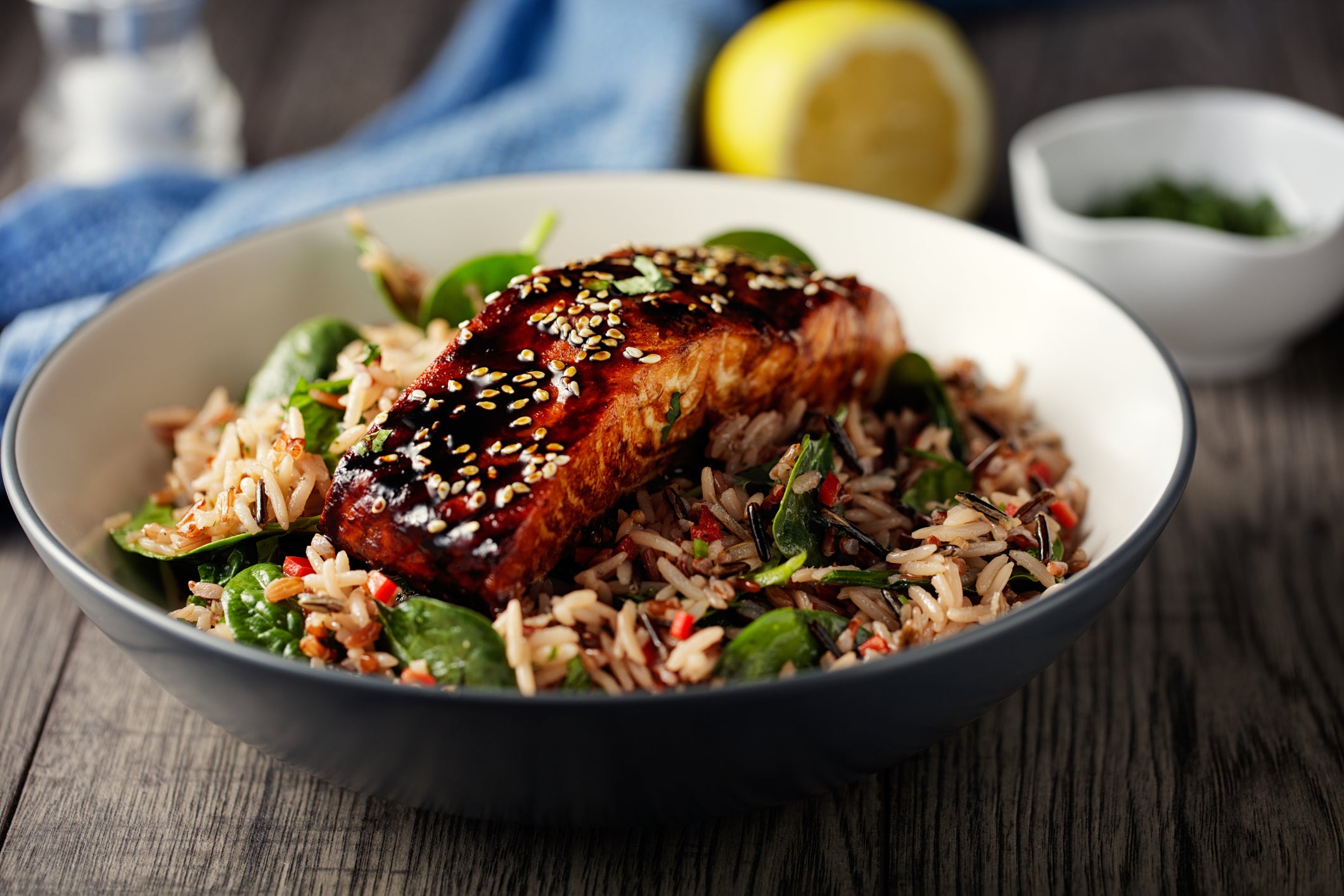 Grilled Teriyaki Salmon with a wild rice salad with baby arugula in a bowl on a dinner table