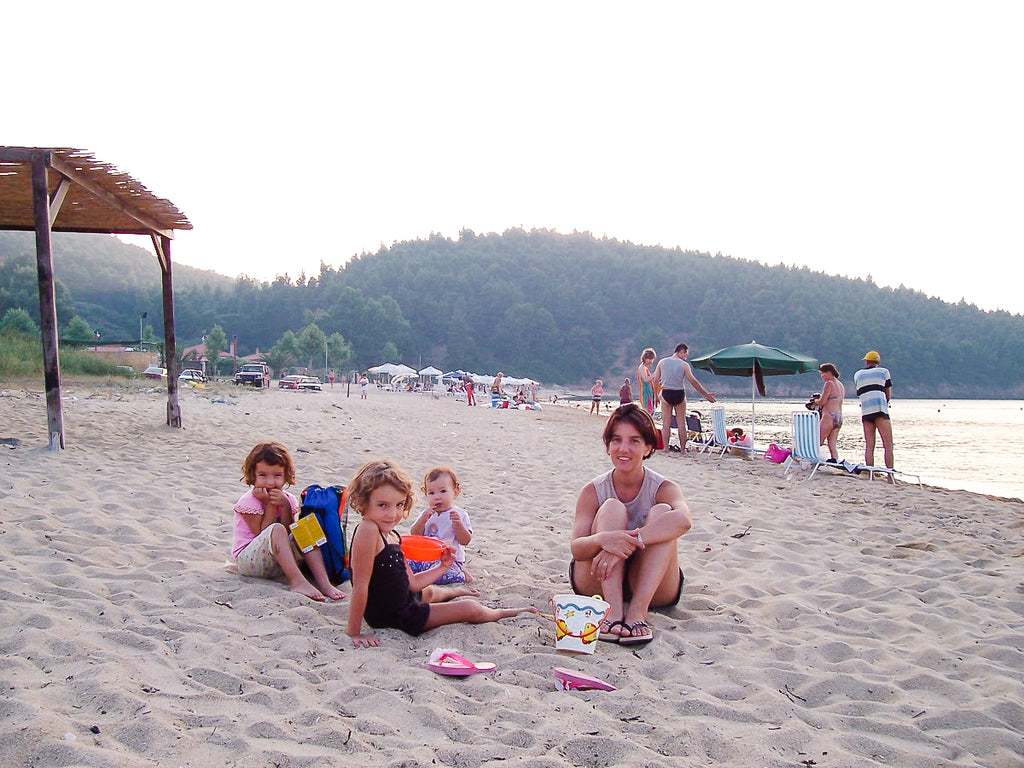 Elli Milan and her three daughters smiling and playing on the beach in Greece