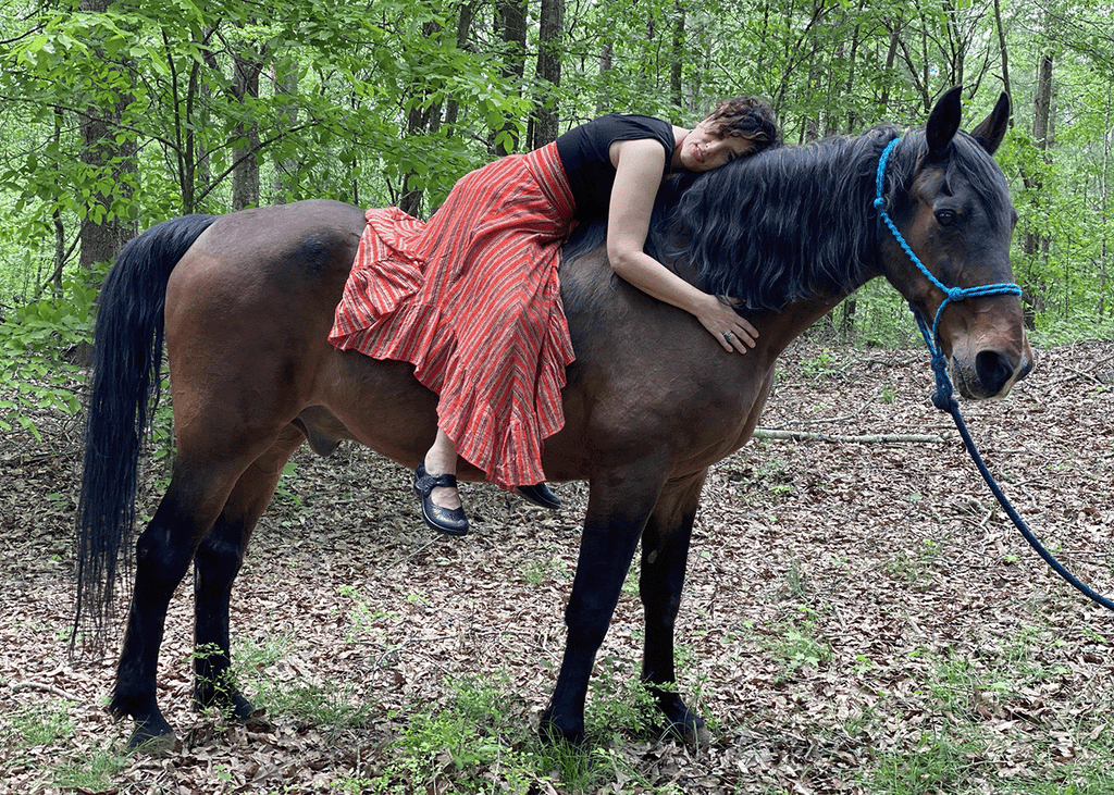 Elli Milan embracing her horse beau in the forest