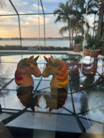 Two unicorn figurines facing each other inside of a beautiful Florida home with a sunset sky visible through the windows