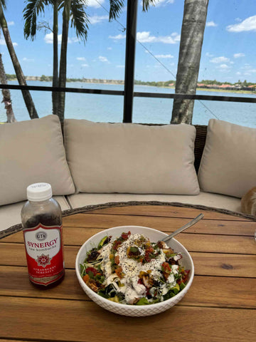 Elli's round couch sits behind a table and in front of a huge window with a gorgeous lake view.