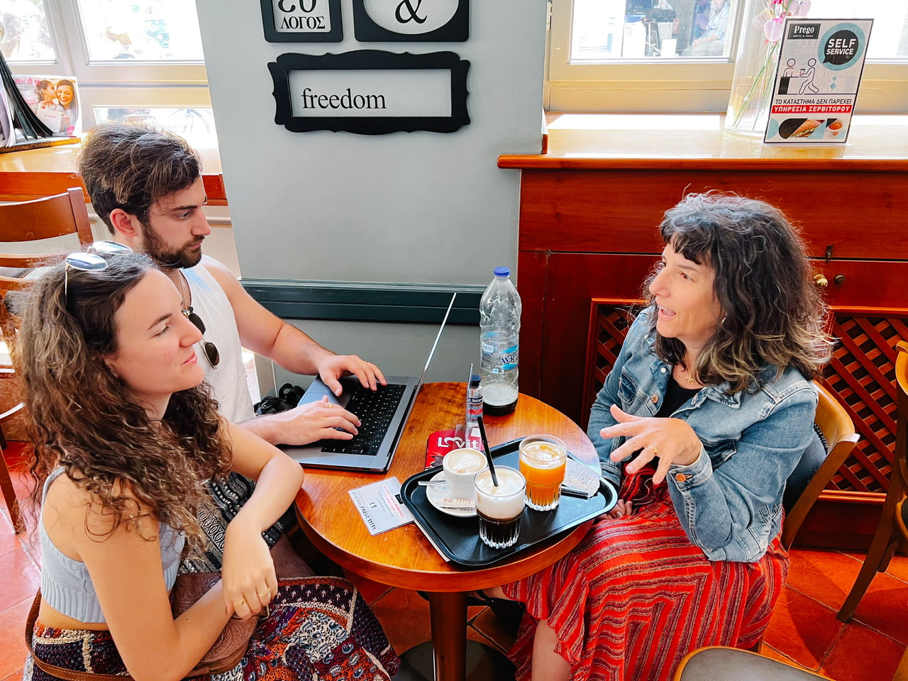 Elli Milan, Dimitra Milan and Jake Dunn discuss The Outstanding Artist at a cafe in Nafplio, Greece