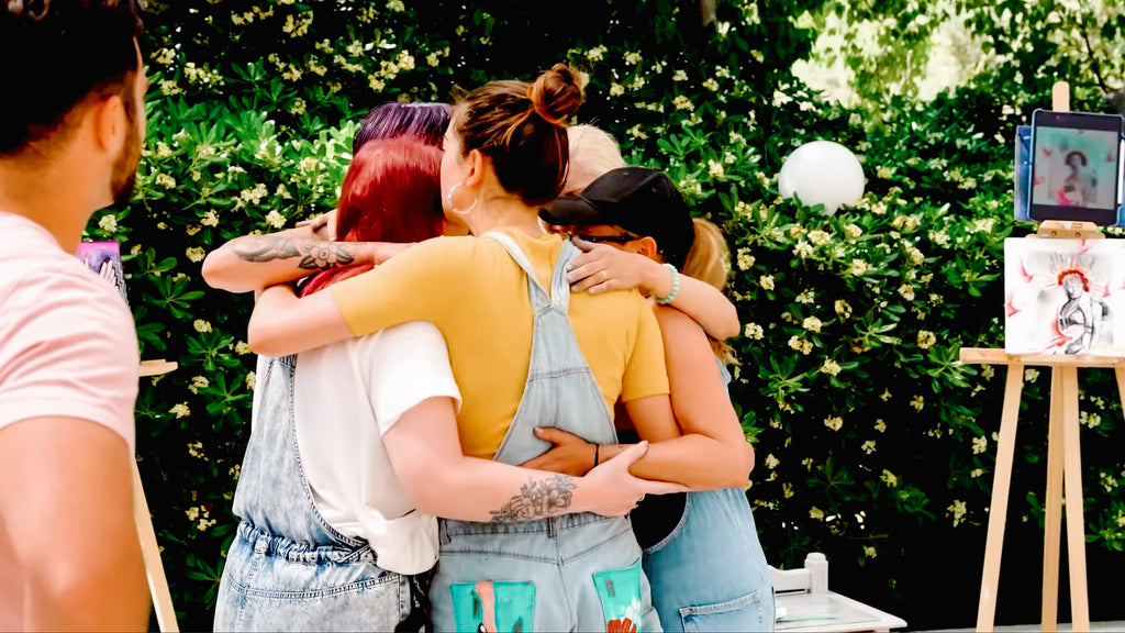 Season 3 contestants of The Outstanding Artist hug each other after painting challenge