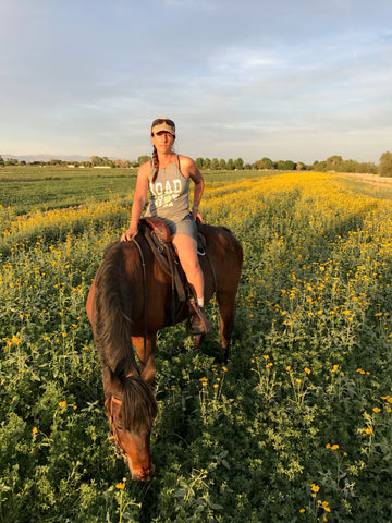 Elli Milan riding her horse Beau in a pasture