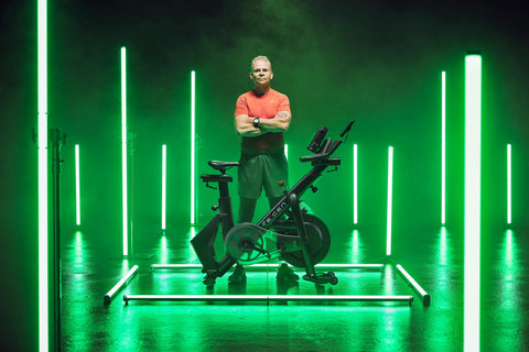 Man standing next to the electricity-generating indoor bike