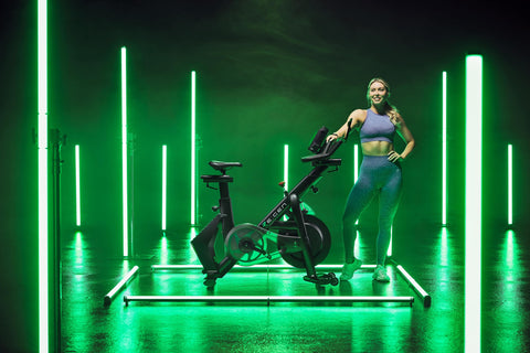 RE:GEN bike in a green-lit studio with female next to it