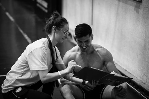 Young female showing young athlete something on an ipad in a black and white image