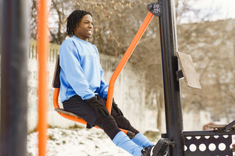 Male person of colour on an outdoor piece of gym equipment