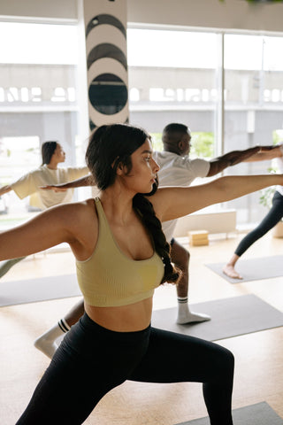 Female in warrior yoga pose in a brightly lit studio