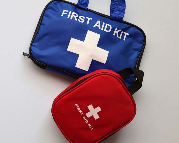 Blue and red first aid kit bags lying on white background