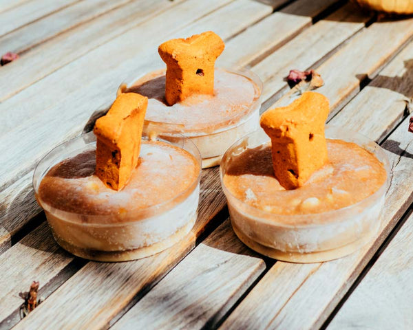 Three peanut butter bone cupcakes for dogs sitting on wooden surface