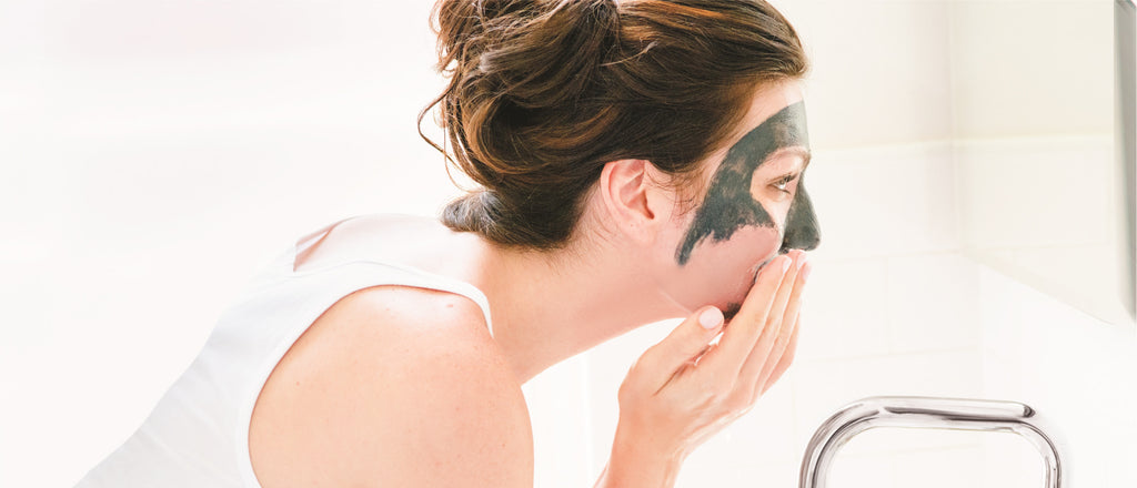 Female applying a mud mask to her face