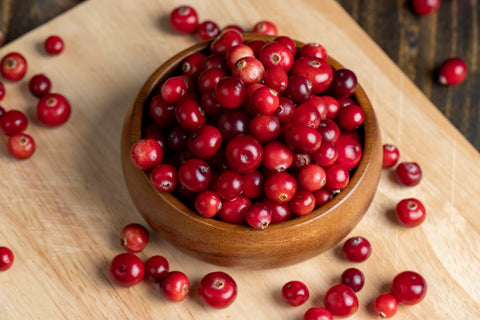 Fresh cranberries in a wooden bowl on a board