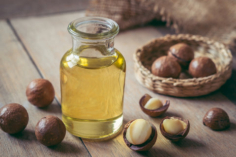 Macadamia nuts on a board and a small bottle of macadamia nut oil