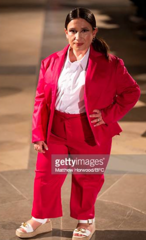 A petite brunette woman, standing at under 4ft 11, is dressed in a bright red suit and white shirt.