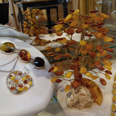 Amber bracelet and pendant are displayed next to a small sculpture of a tree formed by wire and small pieces of amber for leaves.