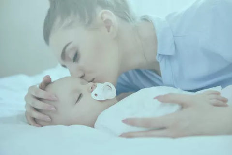 Mamá durmiendo a bebé con chupón