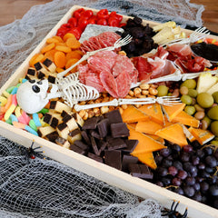 Cheese Tray with multiple cheeses, Halloween Candy and a toy skeleton.