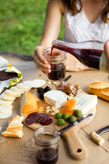 woman sitting over cheese board on picnic table