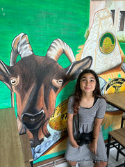 Girl in front of a painting of a dairy goat