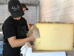 Half wheel of Montgomery's Cheddar with cheesemonger taking off cloth