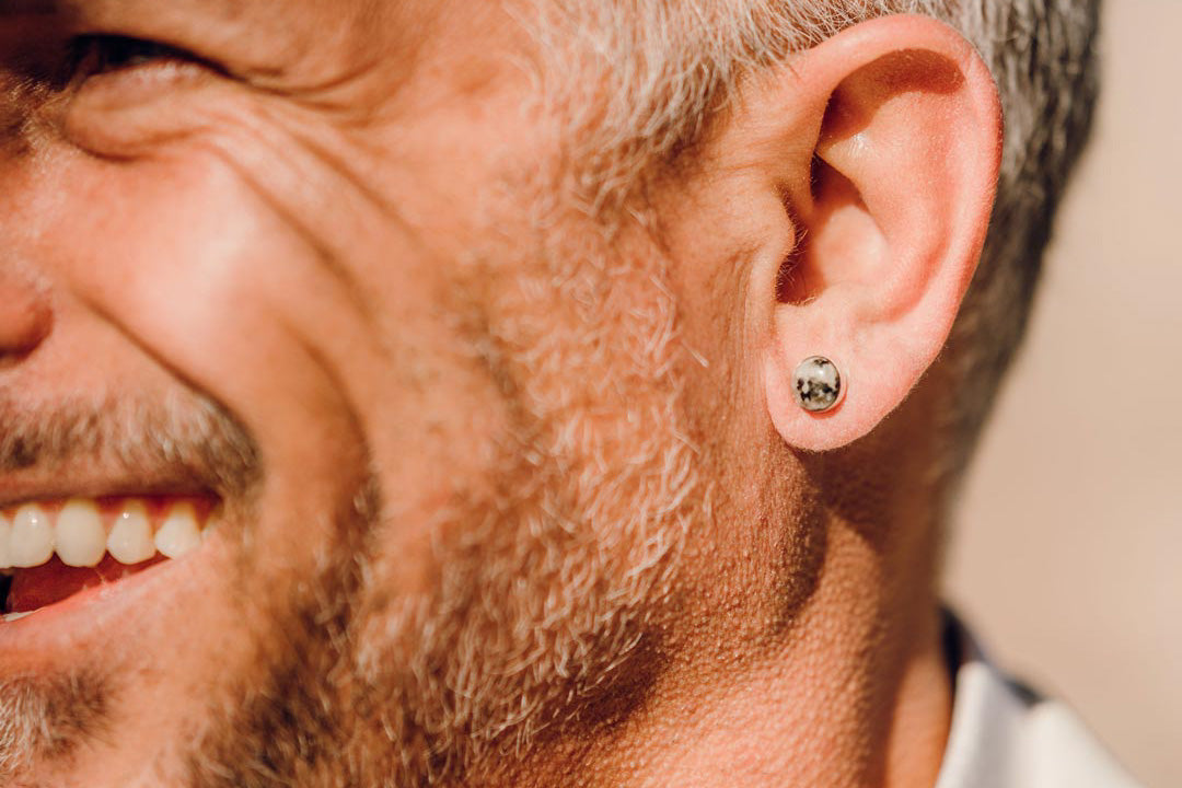 A white male smiles while wearing the Waystone's small confluence stud earrings