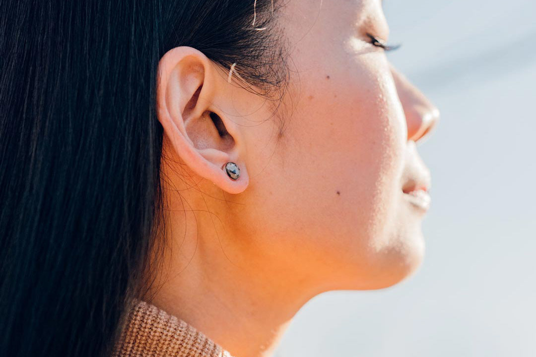 A woman wearing the medium confluence earrings looking at peace with the world