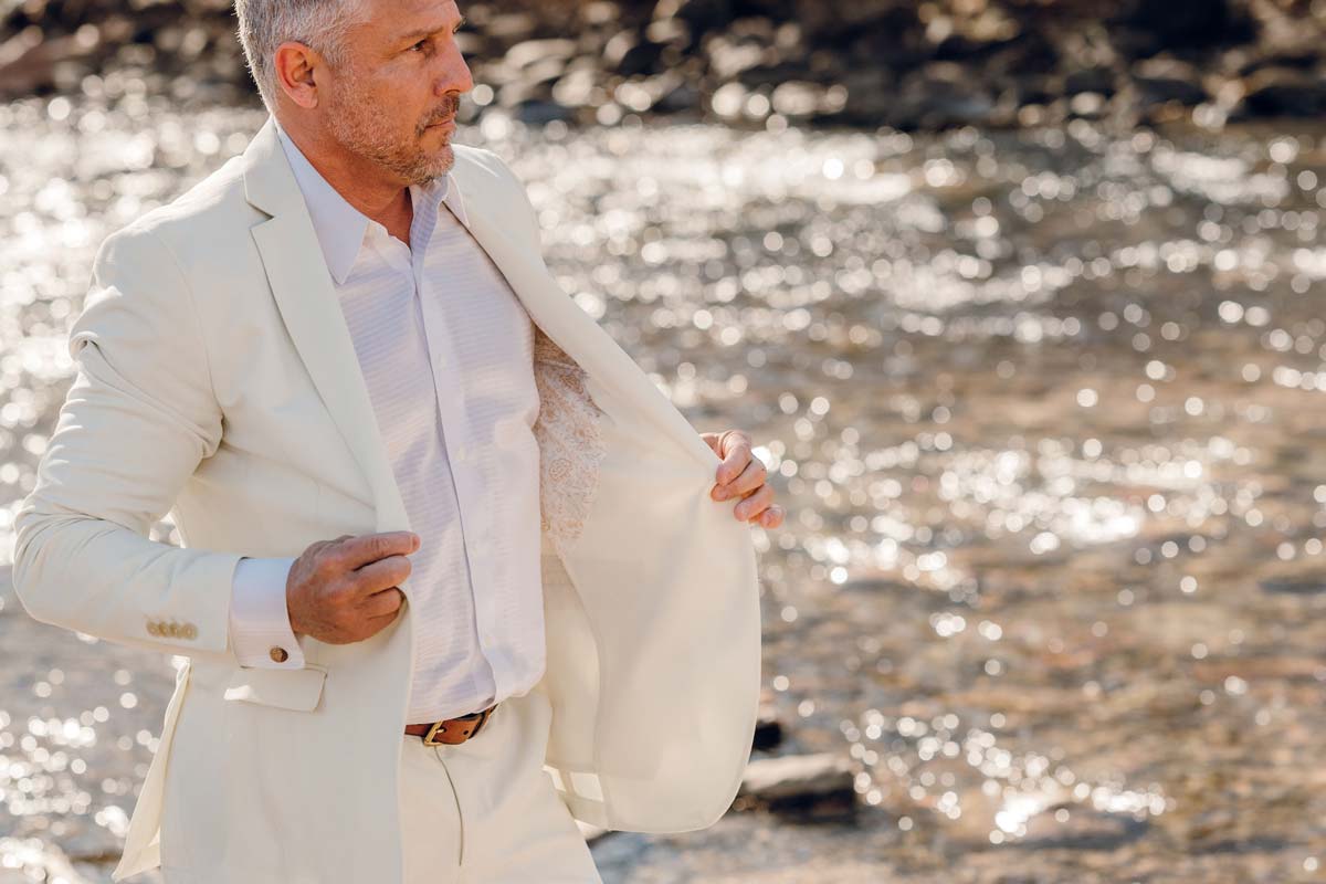 Man dressed for a wedding in a white suit with natural stone cufflinks 