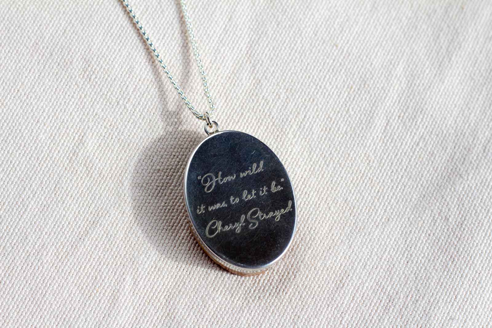 A quote engraved on a sterling silver necklace reads, "How wild it was to let it be" by Cheryl Strayed