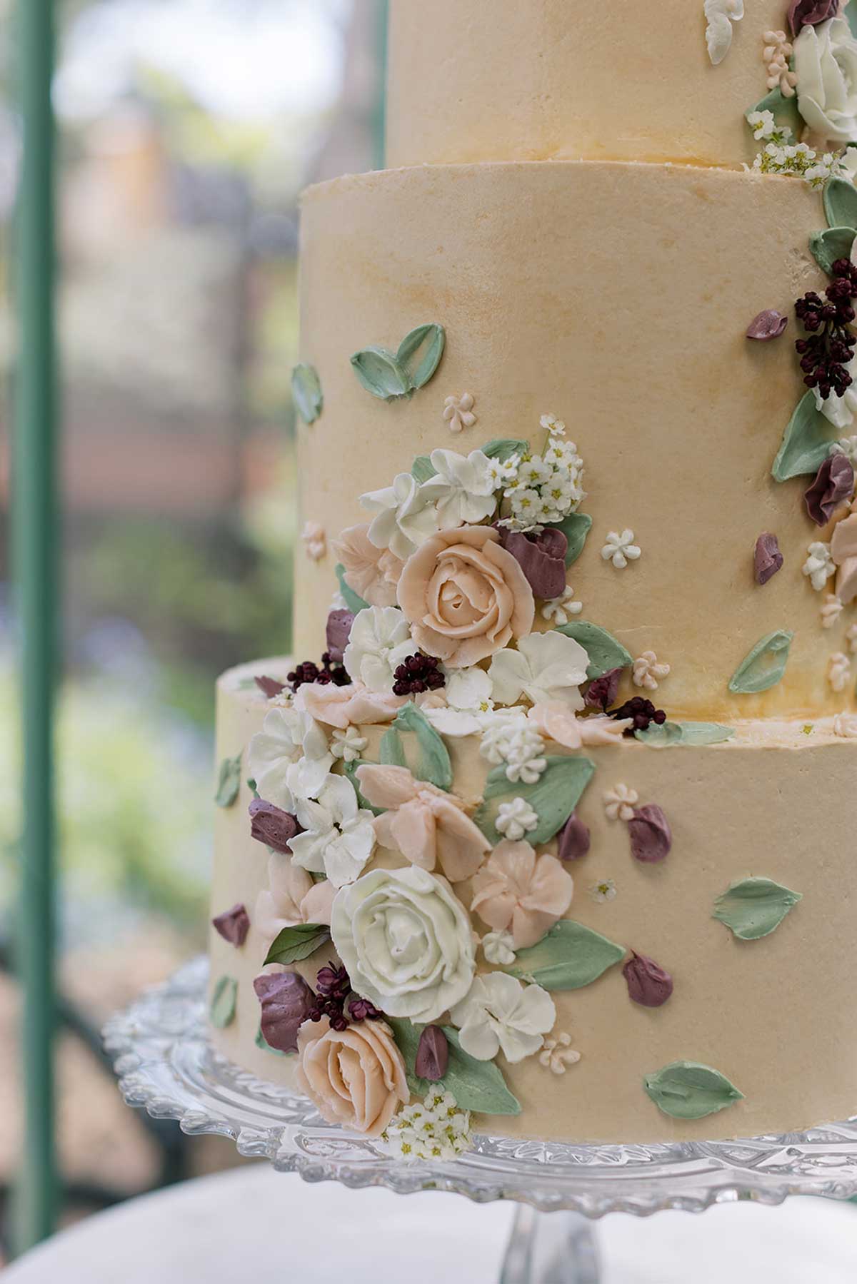 Mauve, lilac, maroon, and cream tiered wedding cake with florals