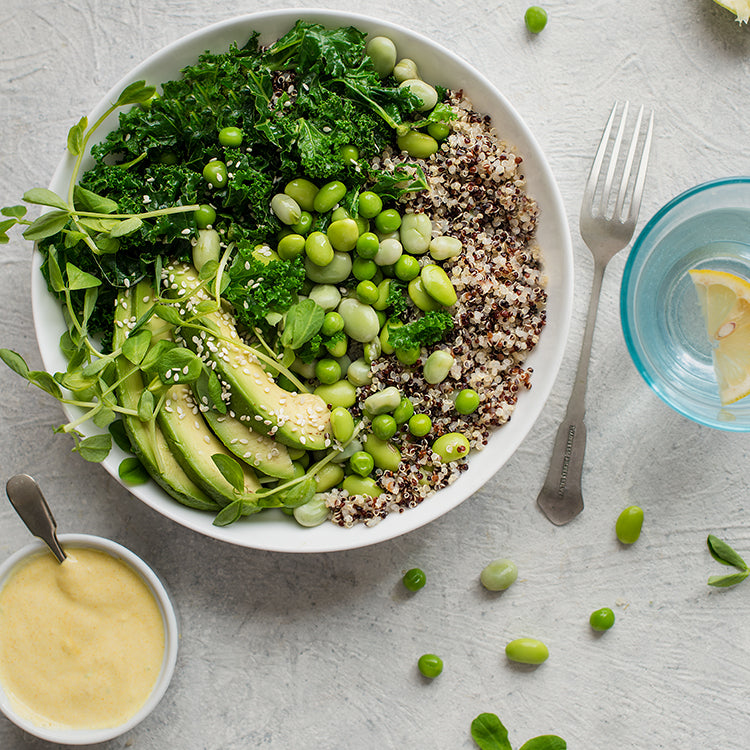 Bowl of quinoa topped with a green salad, beans and avocado