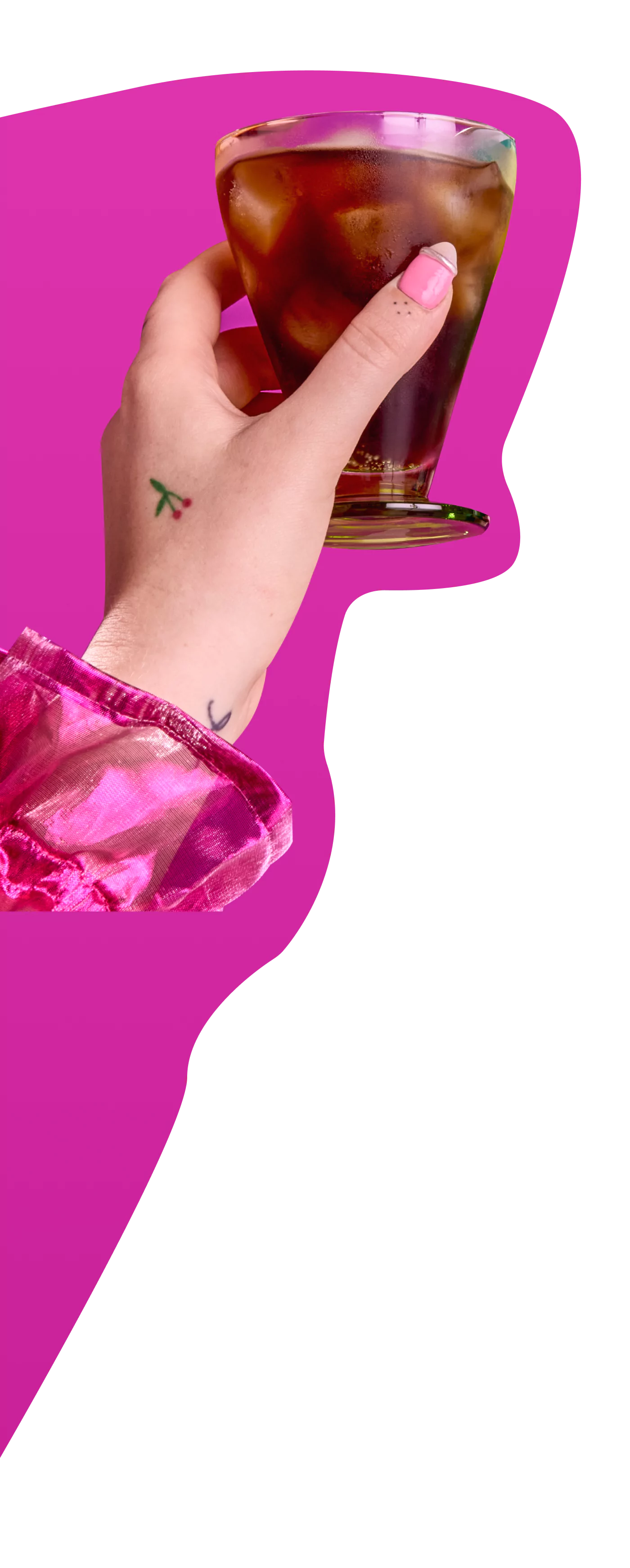 Hand holding a glass of iced coffee against a pink background.