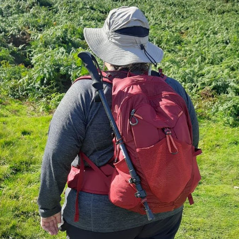 fat woman wearing red backpack and wide-brimmed hat in the outdoors