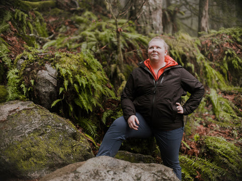 A plus sized woman wearing an Outdoor Research coat in the outdoors