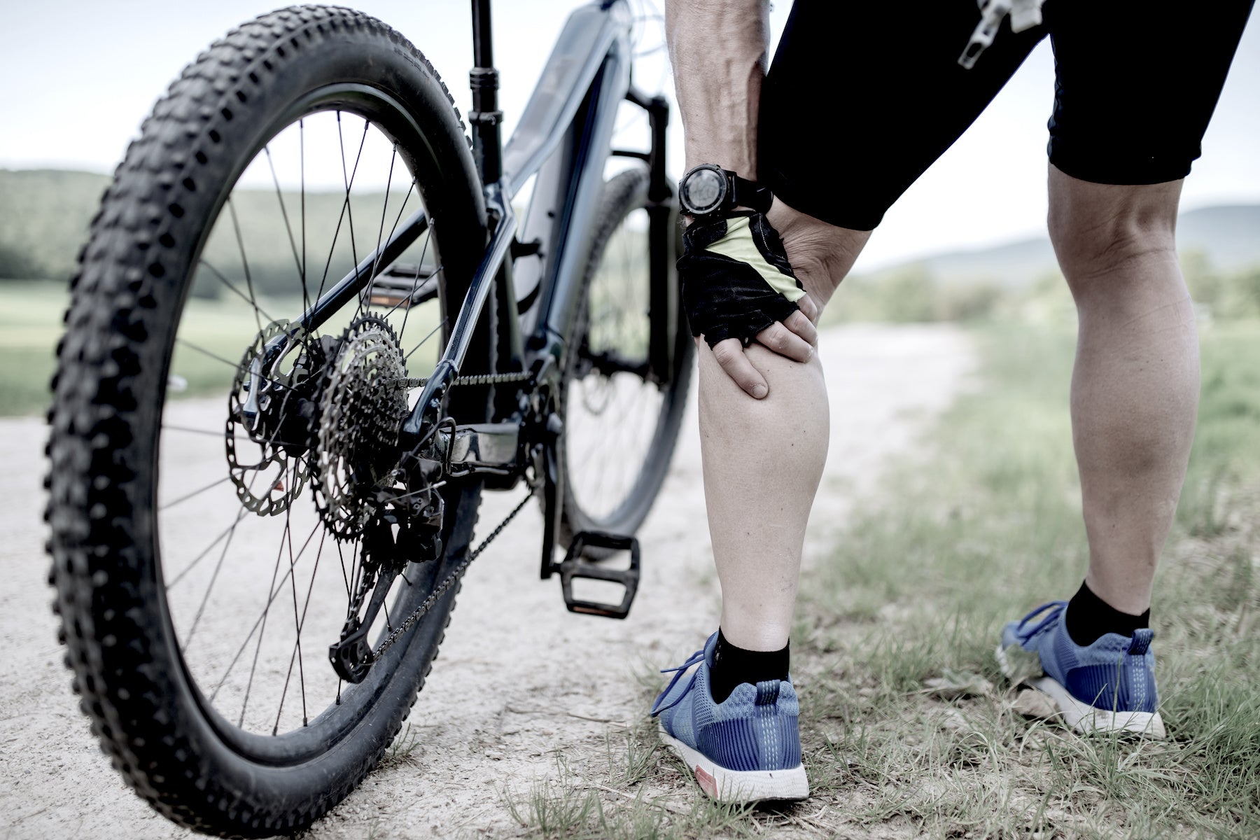 older man exercising on bike holding knee