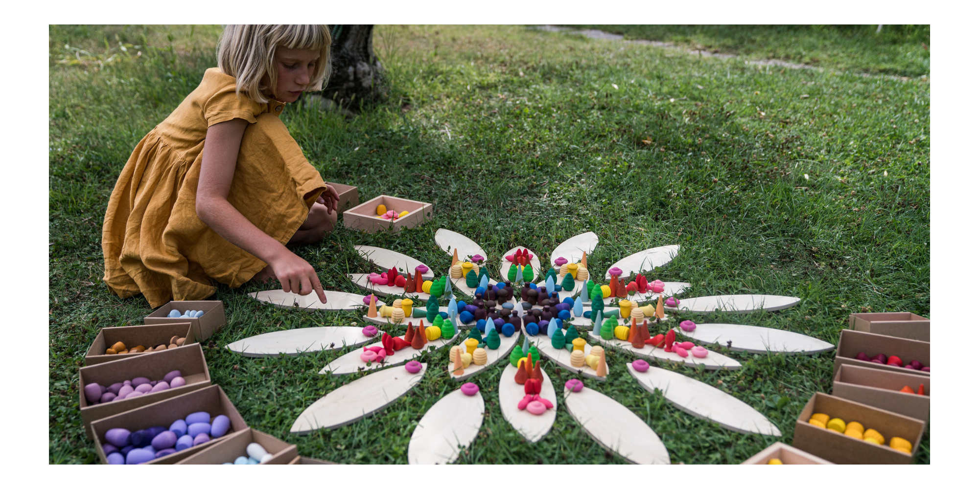 Kind legt buntes Mandala mit Legematerial von Grapat in der Wiese