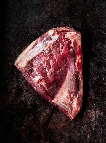 Photo of a raw picanha steak on a dark grey background