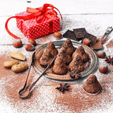 Chocolate truffles with chocolate dust in a dessert bowl with tongs, a red gift box in the back