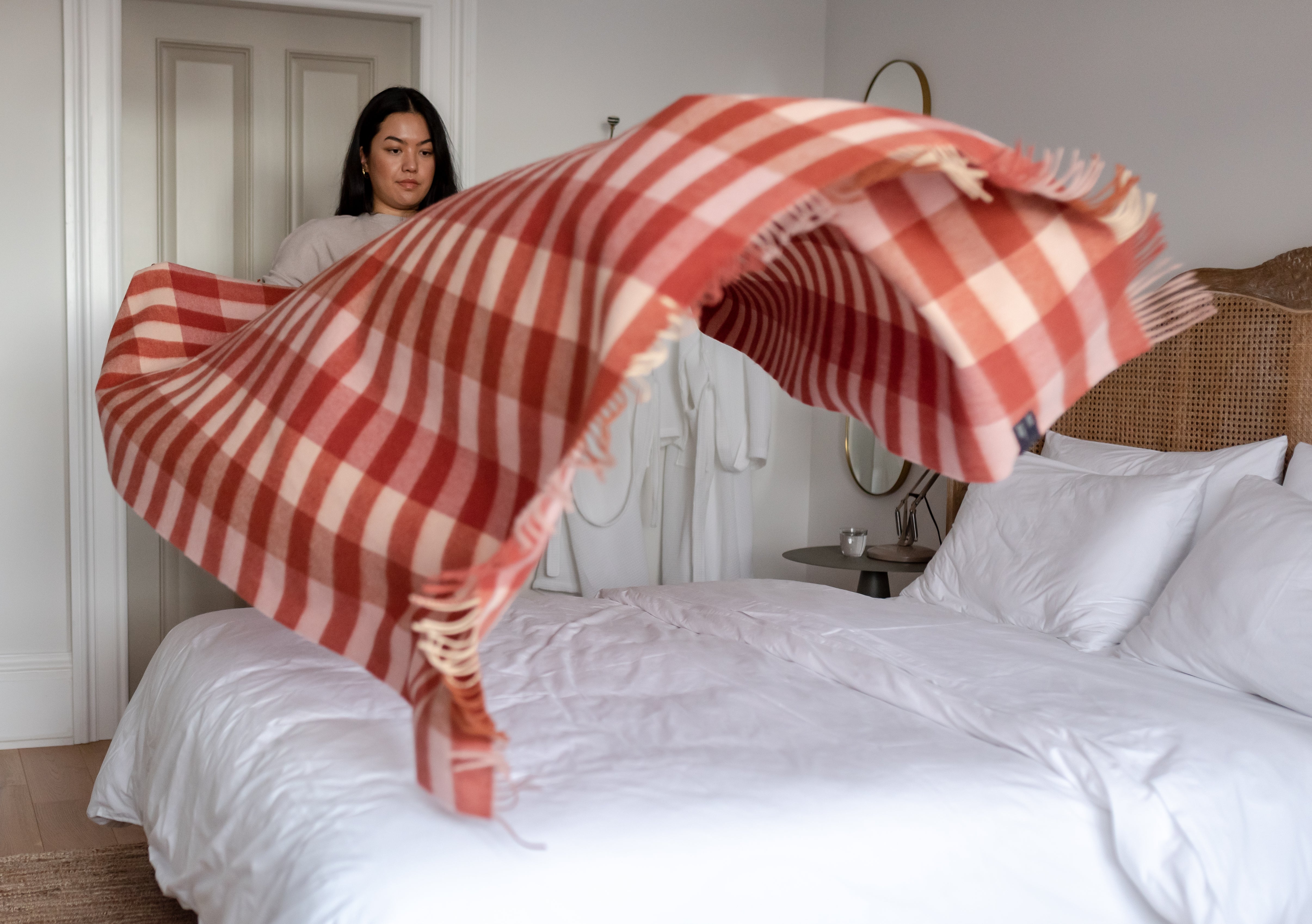 A girl making the bed and draping a blanket across it in hopes of getting a good night's sleep