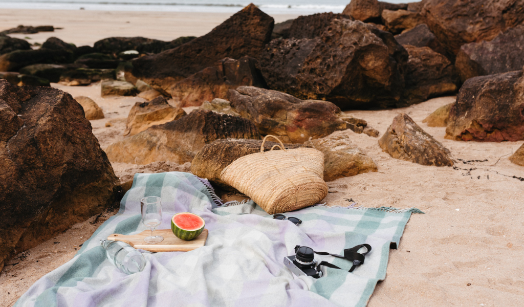 Eine lilafarbene Picknickdecke, die am Strand liegt