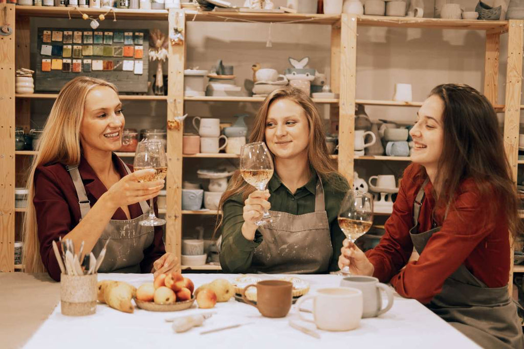 Three cheerful women in a wine and painting class