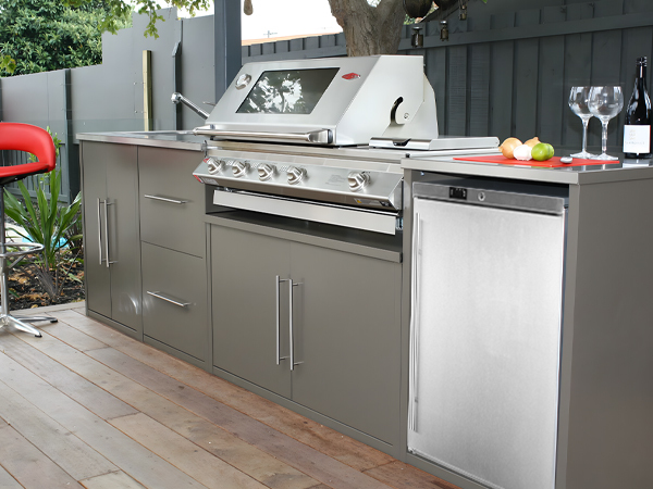 Side view of an outdoor setting with the 5.4 Cu Ft Stainless Steel Undercounter Outdoor Refrigerator installed in the barbecue grill station under the counter