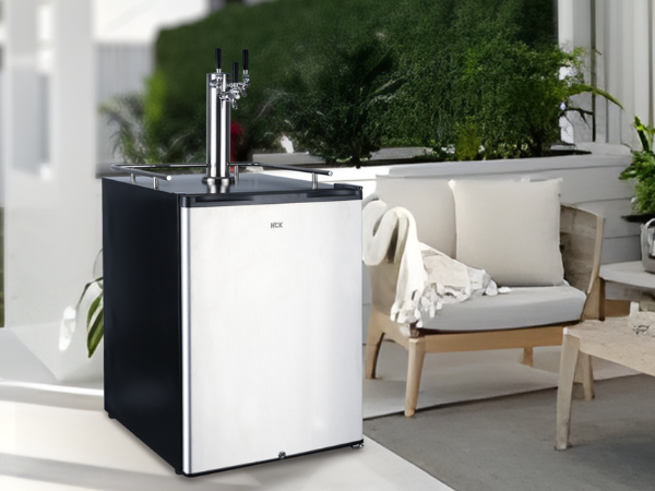 User Side view of a outdoor setting with the 6.53 Cu Ft Outdoor Kegerator Stainless Steel Refrigerator 230 Cans positioned next to an outdoor sofa