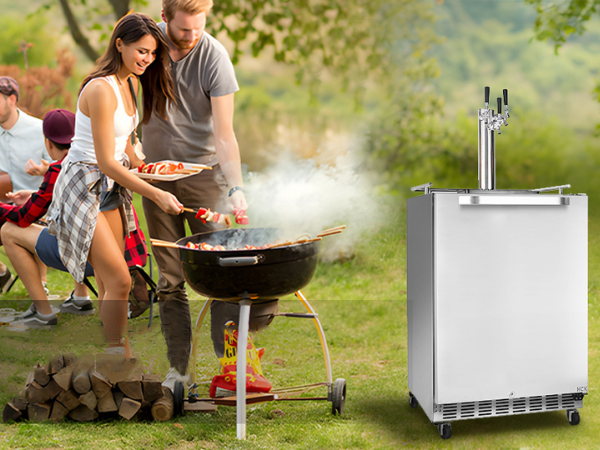 Front view of a camping site featuring the 6.04 Cu Ft Undercounter Kegerator Outdoor Beverage Fridge positioned next to two people cooking on a camping grill. In the background, a group of people can be seen having a cheerful chat