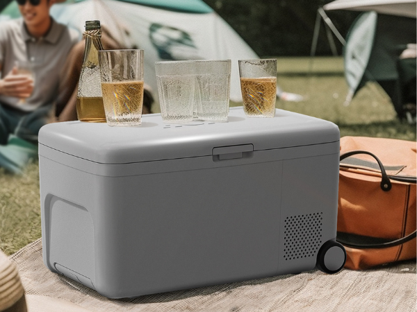 Side view of a 0.6 Cu ft Camping Outdoor Refrigerator in a camping setting, with glasses placed on top.