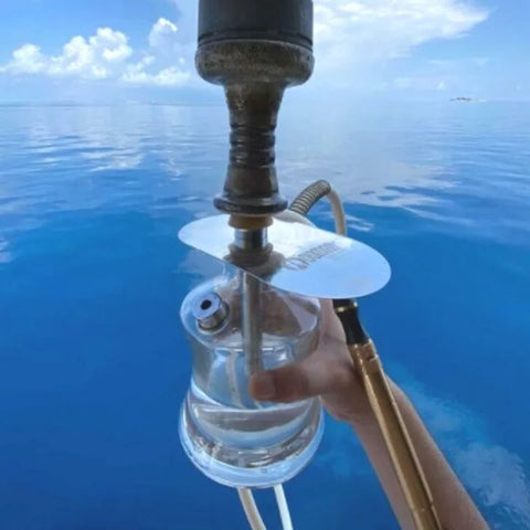 समुद्र में हाथों में हुक्का पकड़े हुए ओडुमन एन2 ट्रैवल हुक्का। फ़नल बाउल और एचएमडी डिवाइस का उपयोग किया गया